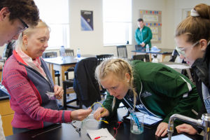 Caring adults challenge and support students. Here, chemistry students are guided through an experiment by their teacher.